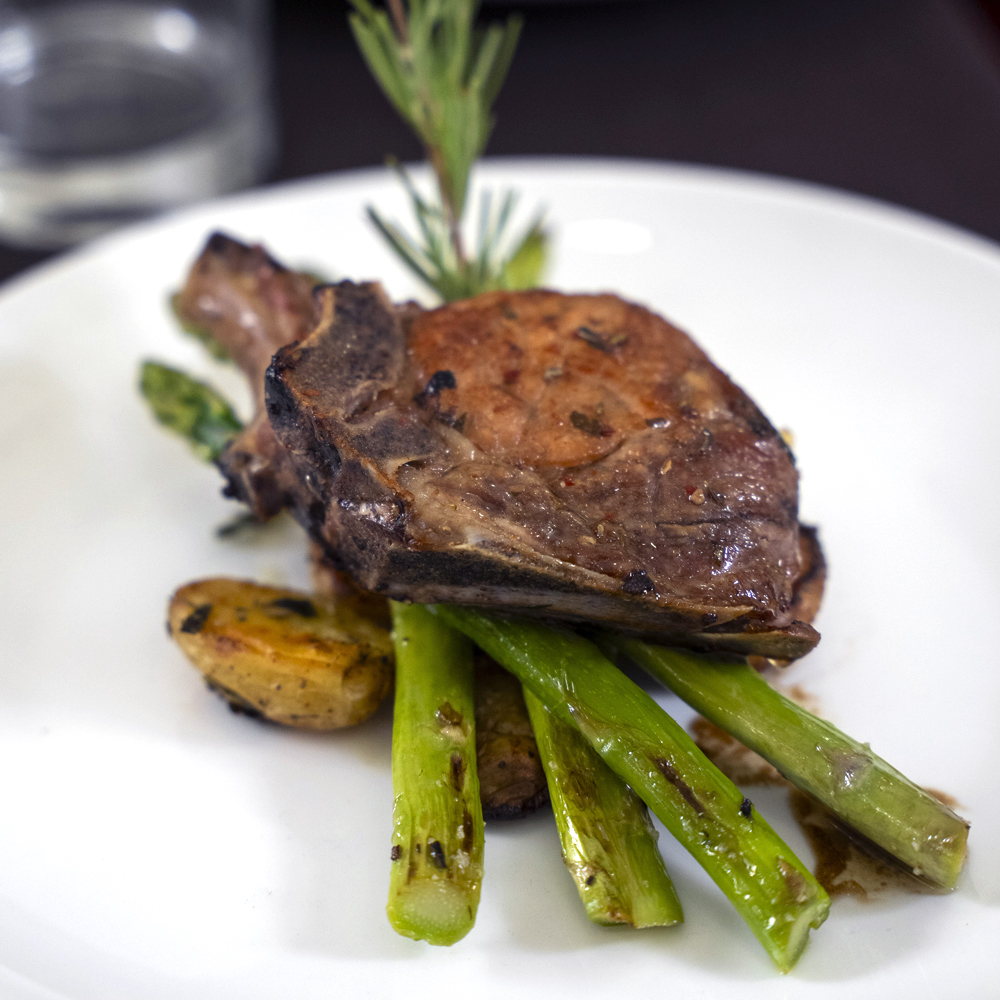 Plated lamb chop with roasted potatoes and asparagus at Atrium’s dining room